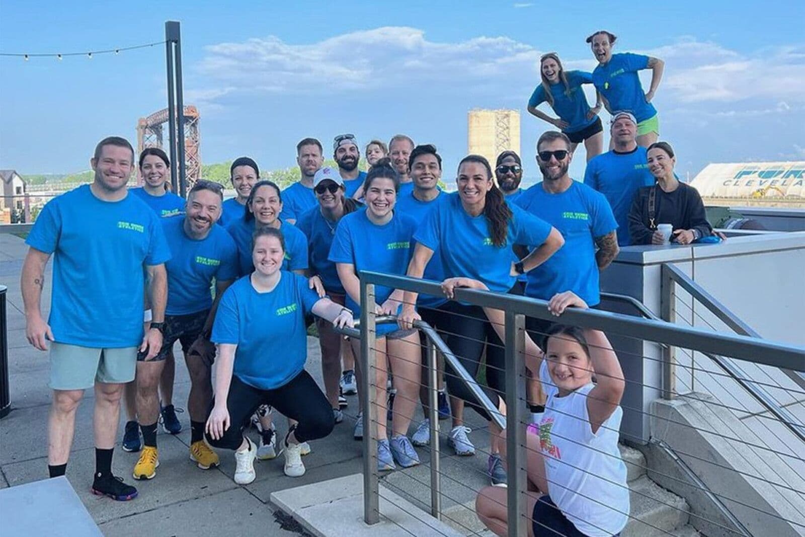 A big group of Erie Shore Athletics members in matching blue shirts on a Cleveland waterfront