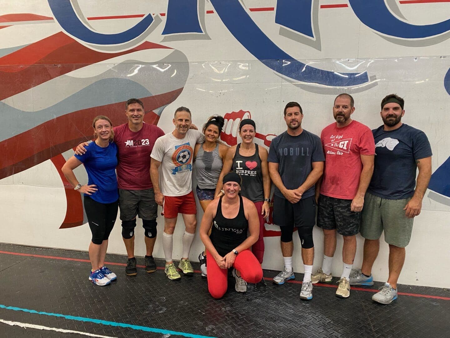 Erie Shore Athletics members after a workout, in front of the gym mural