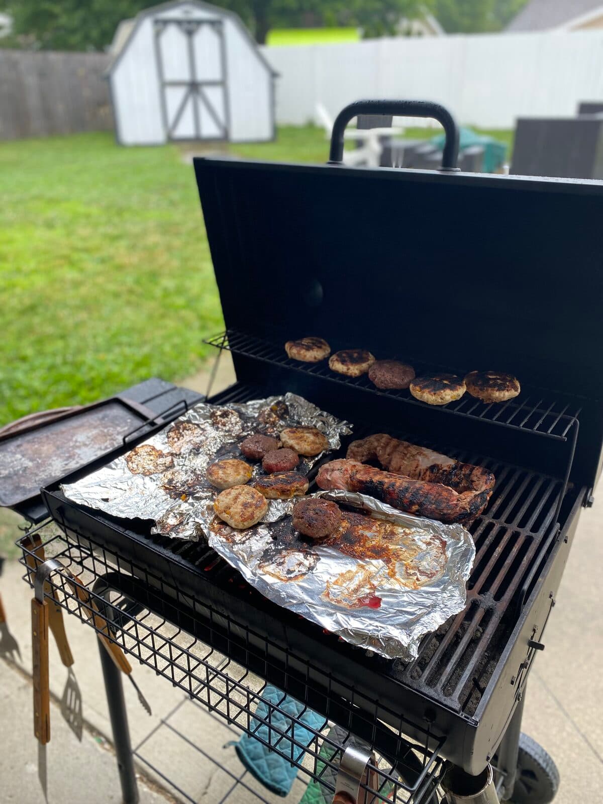 Burgers and sausage cooking on a backyard grill